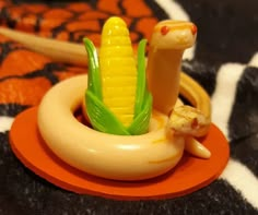 a toy snake and corn on the cob are sitting in a small orange bowl