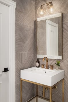 a white sink sitting under a bathroom mirror next to a wall mounted faucet