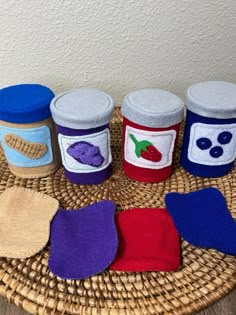 four jars are sitting on a wicker basket with two mitts and one is covered in felt