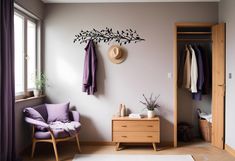 a room with a chair, coat rack and purple blanket on the floor next to a window