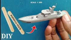 a hand holding a toy model of a battleship