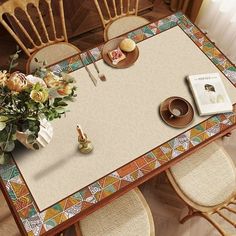 a table with flowers and plates on it in the middle of a room that has wooden chairs around it