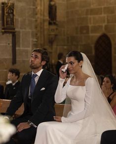 the bride and groom are sitting down at their wedding ceremony, one is talking on his cell phone