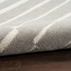 a close up of a rug on a wooden floor with white and gray stripes in the middle