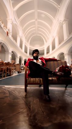 a man sitting on top of a couch in a room filled with tables and chairs