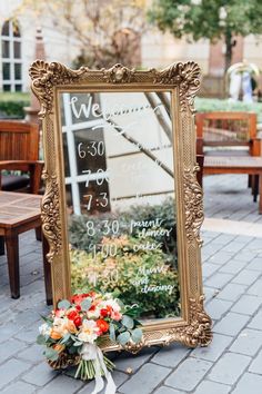 a sign that is on the ground with flowers in front of it and some benches behind it