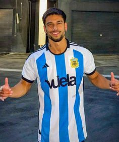 a man in a blue and white striped shirt giving the thumbs up