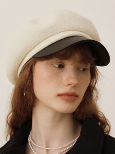 a woman with red hair wearing a white hat and pearls on her necklace is looking at the camera