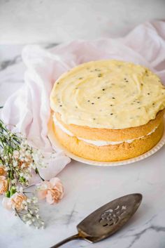 a cake sitting on top of a white plate next to a knife and flower bouquet