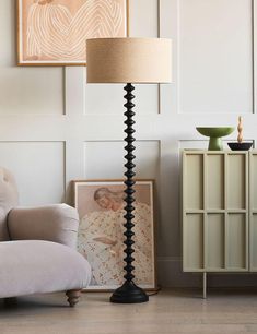 a living room with a chair, lamp and pictures on the wall