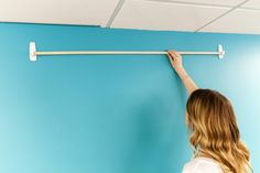 a woman is painting the wall with blue paint and white rollers in an office