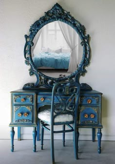 an ornate blue vanity with mirror and chair