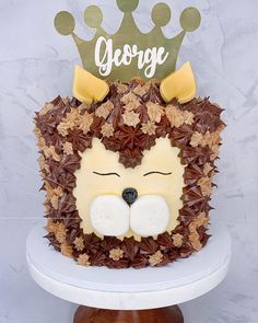 a cake decorated with leaves and an animal's face is on top of a pedestal