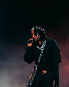 a man with dreadlocks holding a microphone in his right hand while standing on stage