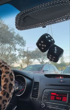 the interior of a car with dice hanging from it's dash board and steering wheel