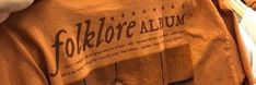 a person wearing an orange t - shirt with the words folklore album on it