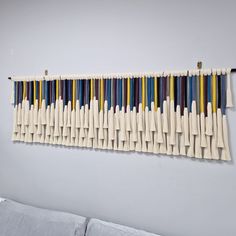 a wall hanging on the side of a white wall with multicolored toothbrushes