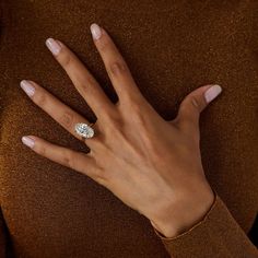 a woman's hand with a diamond ring on her left wrist, wearing a brown sweater