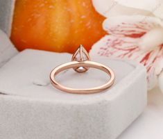 a pink gold ring with an amethorate stone in the center on a white box