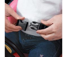 a woman is holding onto her belt as she sits in a pink toy car and holds on to it