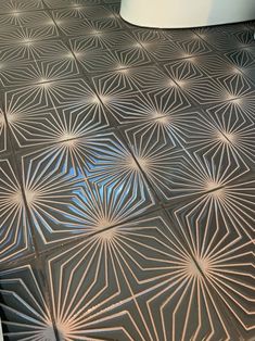 a bathroom floor with an intricate design on the tile and a toilet in the background