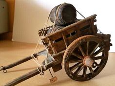 an old wooden cart with two wheels and rope on the front, sitting on a wood floor