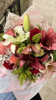 a bouquet of flowers sitting on top of a white paper wrapper in someone's hand