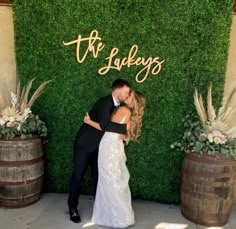 a bride and groom kissing in front of a green wall with the words, the luckys on it