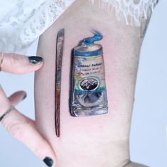 a woman's thigh with a painting brush and watercolor paint can on it