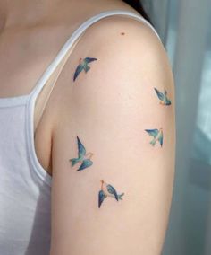 a woman's arm with blue birds flying in the air on her left shoulder