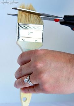 a person is holding a brush with a diamond ring on it's finger and the other hand has a nail clip