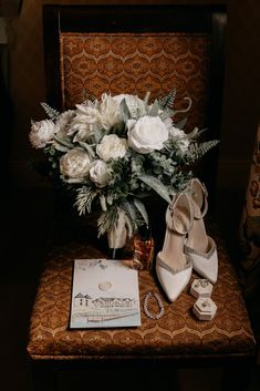 a bouquet of white flowers sitting on top of a chair next to a pair of shoes