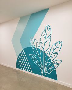 an empty room with a blue and white wall mural on the wall next to a large potted plant