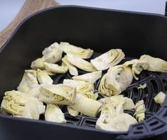 peeled artichokes are being cooked in a large black pan on a table