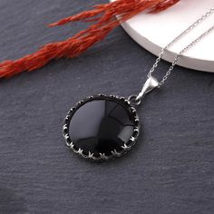 This sterling silver handmade pendant necklace features a stunning black onyx gemstone. The onyx adds a touch of elegance and sophistication to the necklace, making it the perfect accessory for any occasion. The pendant hangs from a sterling silver chain, which adds a touch of shine and sparkle to the necklace. The necklace is perfect for anyone looking for a stylish, timeless piece of jewelry that can be dressed up or down. Are you looking for a truly unique and special piece of jewelry? Look n Onyx Pendant Necklace With Polished Finish, Black Pendant Necklace For Formal Occasions, Classic Black Necklaces With Round Pendant, Classic Black Necklace With Round Pendant, Black Enamel Round Pendant Jewelry, Classic Black Pendant Necklace, Classic Black Round Pendant Necklace, Black Round Pendant Jewelry, Silver Obsidian Pendant Necklace