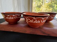 three red bowls with the words caldo vene written in white lettering on them