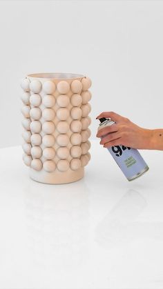 a person is spray painting a vase with white balls on the outside and inside it