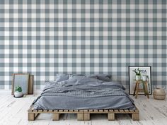 a bed sitting on top of a wooden pallet in front of a plaid wall