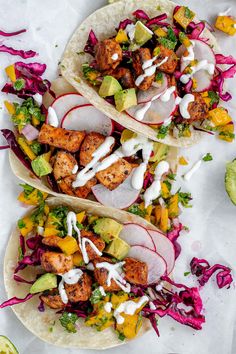 three tacos filled with chicken, radishes and avocado on top of white paper