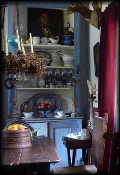 an old fashioned china cabinet in the corner of a room filled with dishes and fruit