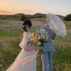 the bride and groom are standing in a field with an umbrella over their heads as the sun sets