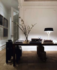 a table with some books and a lamp on it next to a chair in a room