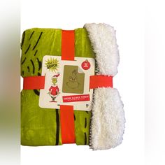 a green and white towel with the grin face on it is wrapped in red ribbon