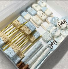 a box filled with lots of blue and white baby shower cake pops next to marshmallows