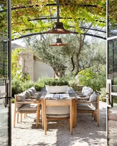 an outdoor dining area with tables and chairs under a pergolated roof, surrounded by greenery