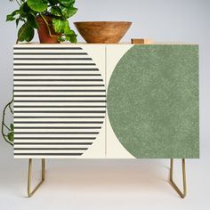 a potted plant sitting on top of a cabinet next to a wooden bowl and plate