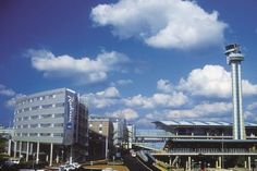 an airport with cars parked in front of it and a control tower on the other side