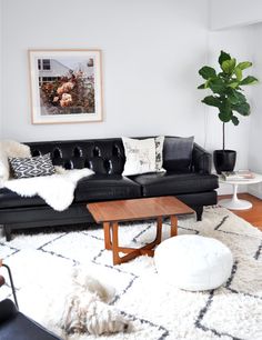 a living room with black leather couches and white rugs on the floor next to a coffee table