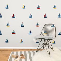 a room with a chair, rug and wallpaper that has colorful sailboats on it