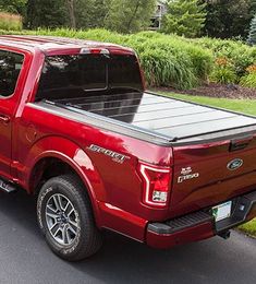 a red truck is parked on the side of the road in front of some bushes